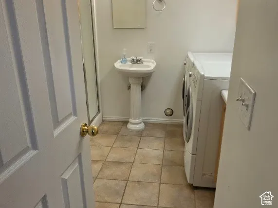 Tiled flooring, pedestal sink, wall-mounted mirror, light fixture, and skylight