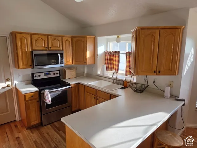 Kitchen featuring wood-finish flooring, light wood cabinetry, white countertops, and stainless steel appliances