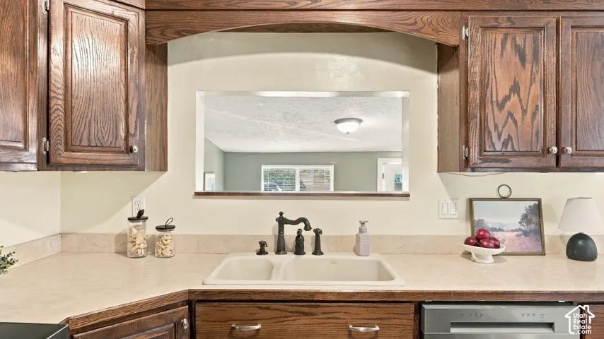 Kitchen featuring stained wood cabinetry, stone-finish countertops, dual-basin undermount sink, and matte black hardware