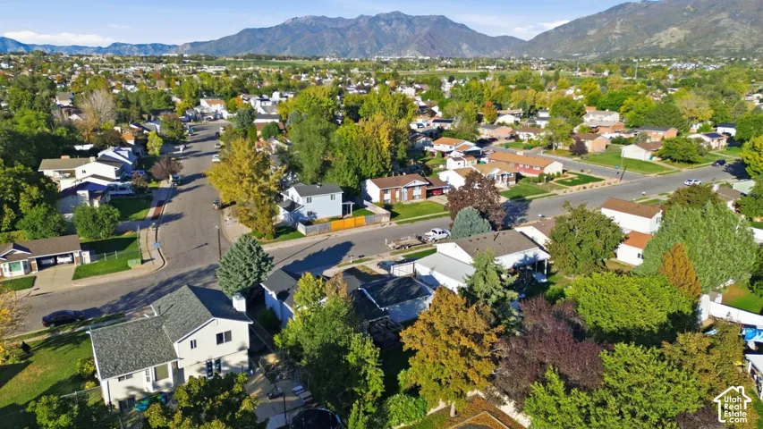Aerial perspective showcasing a residential neighborhood with mature trees and a prominent mountain range backdrop