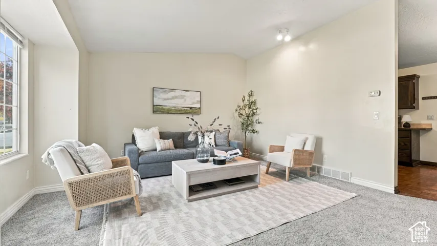 Living area featuring neutral wall paint, high ceilings, carpeted flooring, and a large multi-pane window