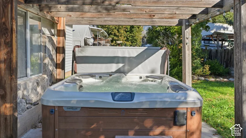 Outdoor space featuring a cedar-style pergola, a built-in spa, concrete patio, and stone veneer exterior siding
