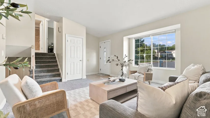 Vaulted ceilings, expansive picture window, and carpeted staircase with decorative banister