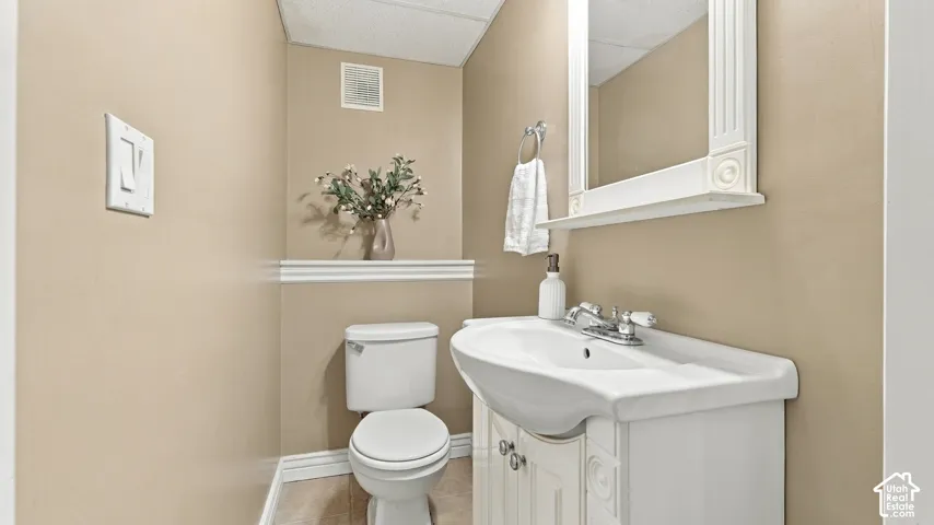 Bathroom featuring a white pedestal-style vanity with storage, a wall-mounted mirror with decorative trim