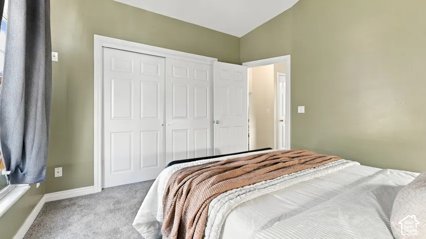 Vaulted ceiling, neutral wall tones, wall-to-wall carpeting, and double-panel sliding closet doors