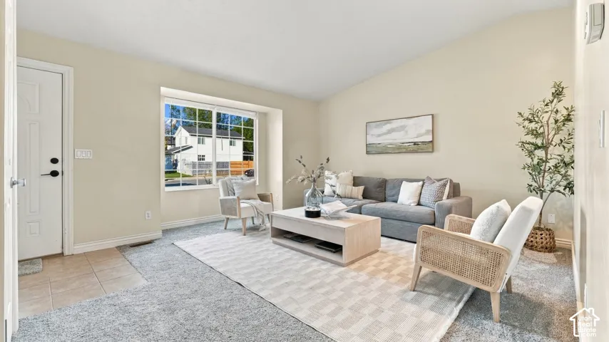 Living space featuring neutral wall paint, carpeting, a multi-pane window, and a tile-surfaced entryway