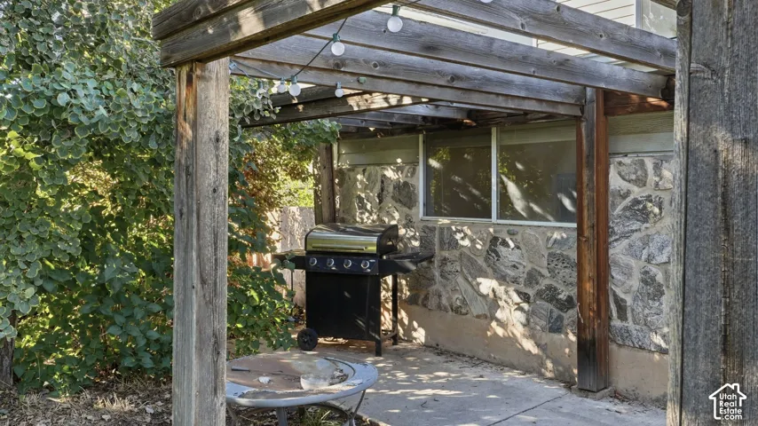 Outdoor patio featuring a timber-framed pergola and natural stone siding