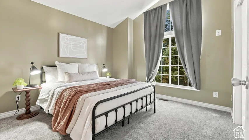 Primary bedroom, Vaulted ceiling, wall-to-wall carpeting, and a tall grid-pattern window with arched transom detail