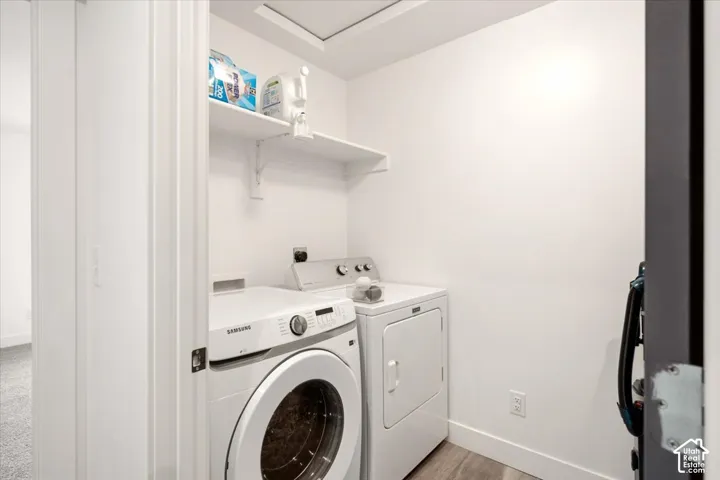 Laundry area featuring a wall-mounted shelving unit and wood-finish flooring