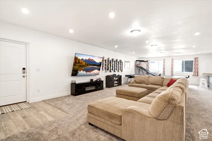 Open-concept area featuring recessed lighting, neutral carpeting, wood-finish flooring at the entry, and multiple windows