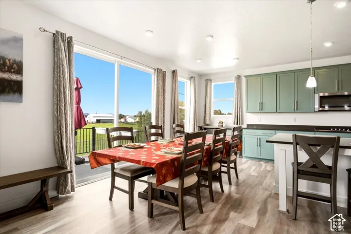 Kitchen area featuring wood-finish flooring, soft-toned cabinetry, a central island with counter seating, and sliding glass doors