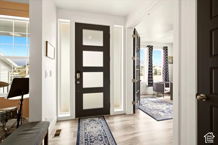 Entryway featuring a dark-finish door with four frosted glass panels, flanked by two full-length sidelights, wood-finish flooring, and a set of French doors