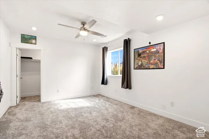 Neutral interior featuring wall-to-wall carpeting, recessed lighting, a ceiling fan with integrated lighting, and a reach-in closet