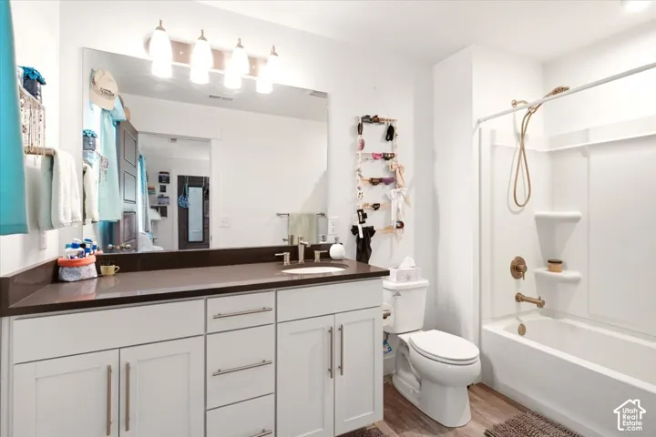 Bathroom featuring a white vanity cabinet with quartz-style countertop, integrated undermount sink, matte bronze fixtures, and wood-finish flooring