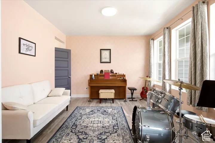 Room featuring wood-finish flooring, patterned wall coverings, large dual-pane windows, and a multi-panel door