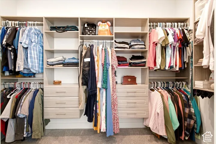 Custom walk-in closet featuring floor-to-ceiling wooden cabinetry, integrated shelving units, dual sets of built-in storage drawers, and tiered clothing rods