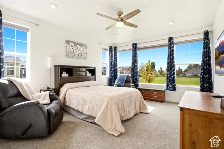 Neutral-toned interior featuring multi-pane windows, recessed lighting, a brushed-nickel ceiling fan, and carpeted flooring