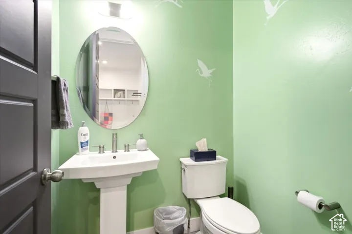Pedestal sink with a widespread faucet, oval wall-mounted mirror, overhead lighting fixture, and chrome hardware