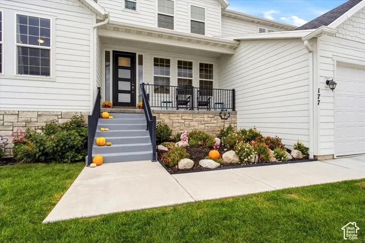 Exterior featuring horizontal lap siding, stacked stone masonry, a covered porch with metal railing, and a contemporary entry door with glass paneling