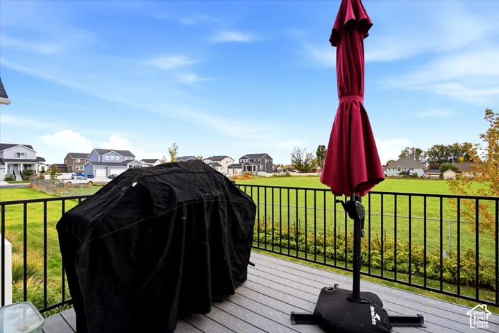 Elevated deck with composite wood-finish decking and black metal railing, overlooking a fenced yard and open green space