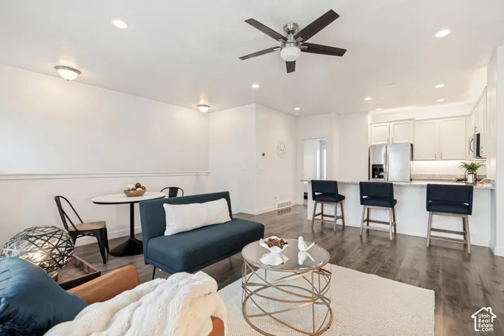 Open-concept living space featuring wood-finish flooring, recessed lighting, a ceiling fan, and a kitchen island with stone countertops