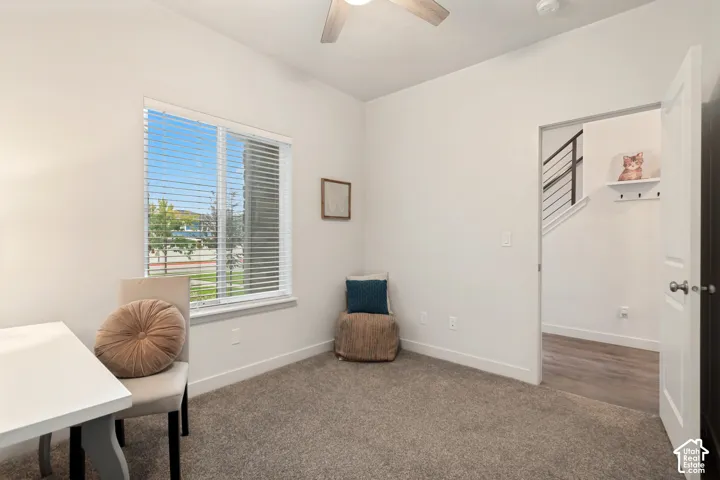 Neutral-toned wall-to-wall carpeting, window with slatted blinds, and ceiling fan with light fixture