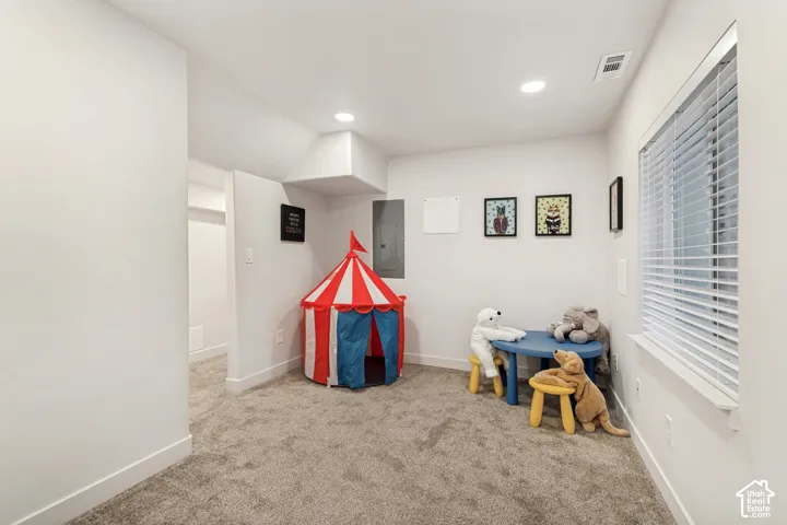 Neutral-toned interior space featuring wall-to-wall carpeting, recessed ceiling lighting, and a horizontal blind window treatment