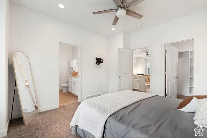 Neutral interior featuring high ceilings, a contemporary ceiling fan, plush carpeting, and two separate entries to a bathroom and a walk-in closet with built-in shelving