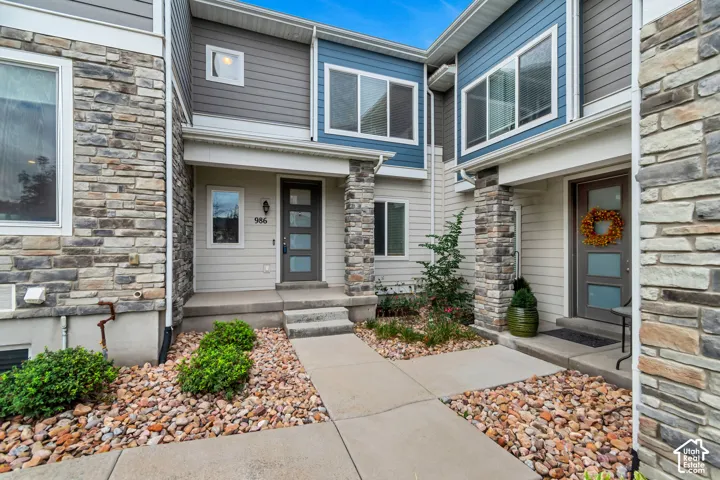 Multi-unit exterior featuring stone veneer accents, horizontal siding, concrete walkways, and tiered entry porches