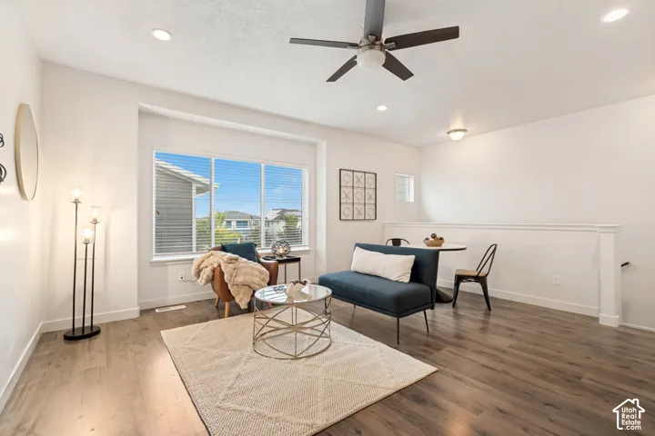 Open living space featuring wood-finish flooring, recessed lighting, a ceiling fan with integrated light fixture, and a large multi-pane window