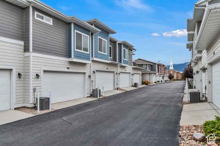 Multi-level exterior featuring horizontal siding, asphalt shingle roofing, attached garages, and exterior wall-mounted lighting