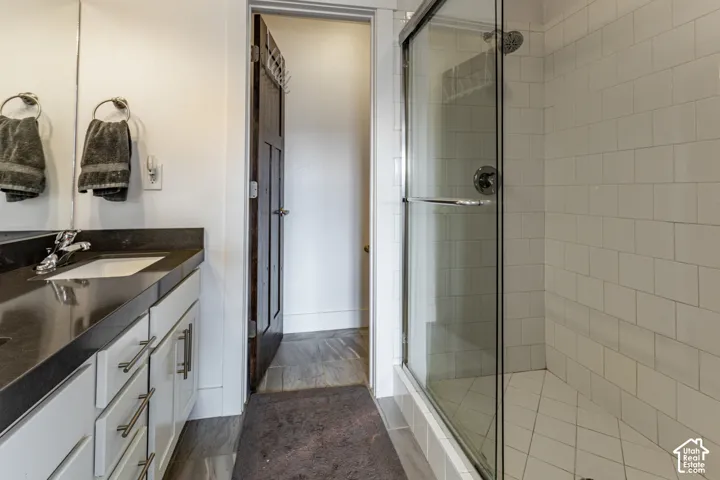 Bathroom featuring a white vanity cabinet with a dark countertop, a walk-in shower with white tile surround and a sliding glass door, and a multi-panel wood door