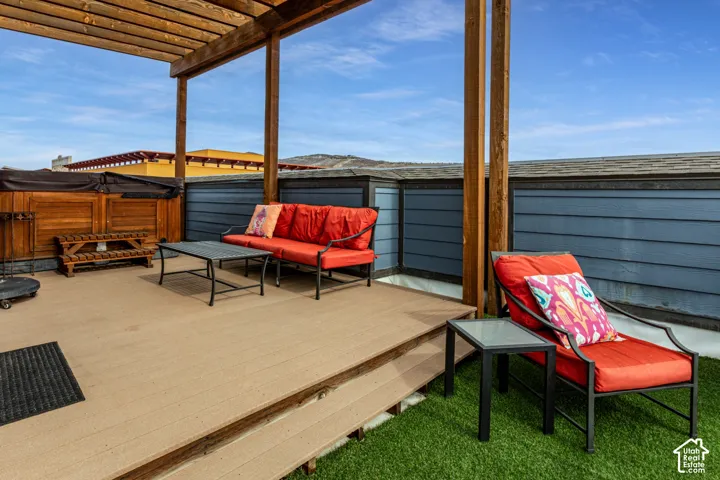 Rooftop terrace featuring composite decking, a wooden pergola, lap siding, and synthetic turf