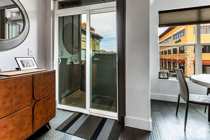 Sliding glass door with dark trim, wood-finish flooring, and oversized windows with retractable roller shades