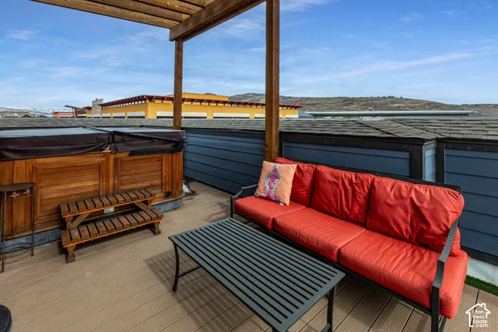 Rooftop deck featuring composite decking, a built-in spa with wood-finish siding, and a wooden pergola