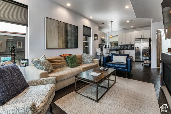 Open-concept interior featuring recessed lighting, wood-finish flooring, white shaker cabinetry, stainless steel appliances, and a glass-tile backsplash
