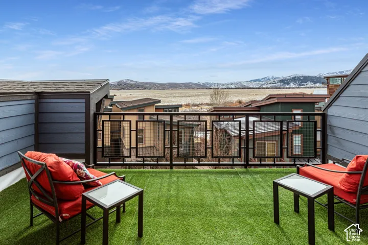 Rooftop deck featuring synthetic turf flooring, black metal grid railing, and panoramic mountain backdrop