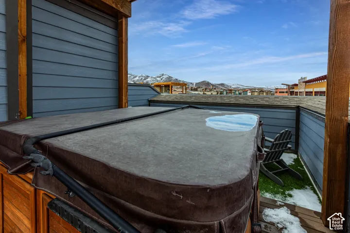 Elevated deck featuring a spa, horizontal lap siding, and mountain backdrops
