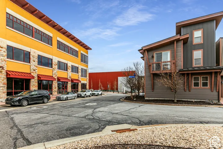 Mixed-use exterior featuring stucco and stone masonry, multi-level metal siding, integrated balconies, and expansive glass windows with red metal awnings
