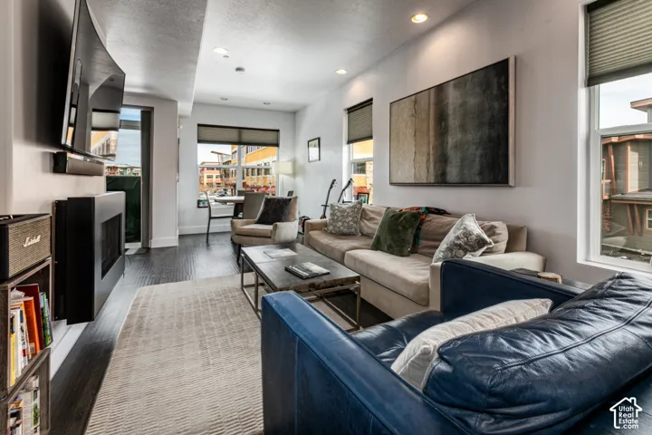 Wall-mounted linear fireplace, wood-finish flooring, recessed lighting, and large windows with integrated shades