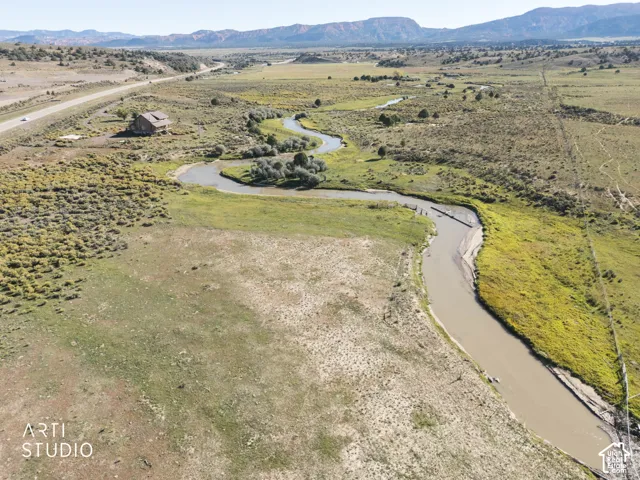 Extensive acreage featuring a winding creek, natural terrain, and a mountain backdrop