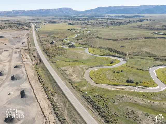 Aerial expanse featuring a meandering waterway, sweeping plains, and prominent mountain backdrops