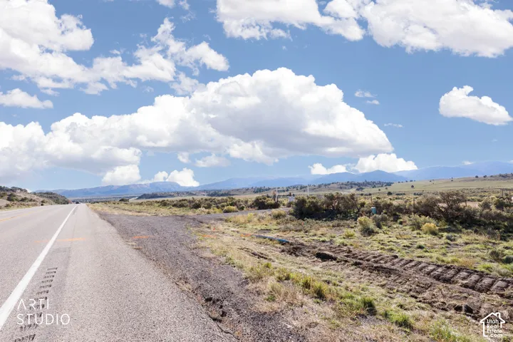 Expansive undeveloped land featuring native scrub brush, unpaved terrain, and prominent mountain range backdrop