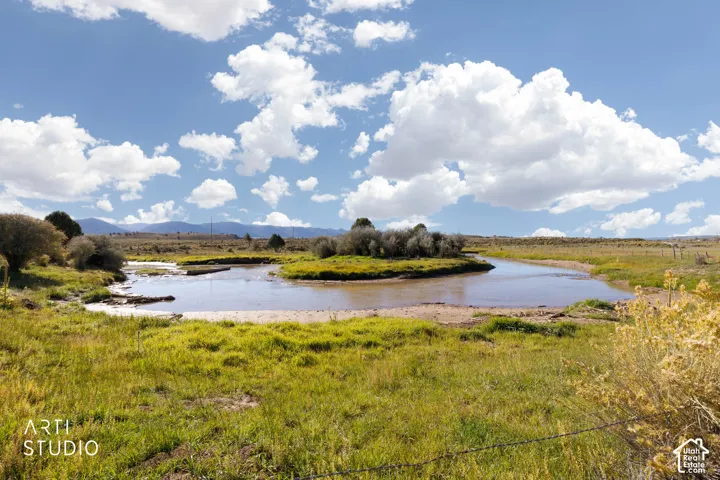 Expansive acreage featuring a natural creek, riparian vegetation, open meadow, and distant mountain topography