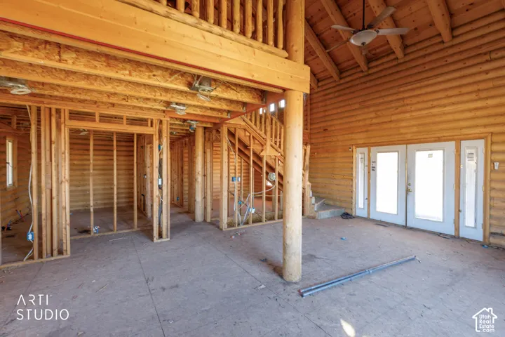 Interior space featuring exposed log walls, vaulted ceilings with exposed timber beams, a wooden staircase, and dual entry doors