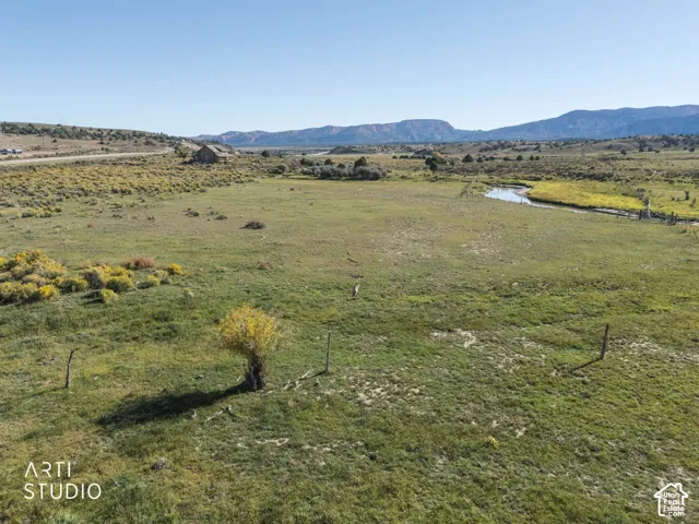 Expansive acreage featuring natural meadowland, a winding creek, mature trees, and a mountain range backdrop