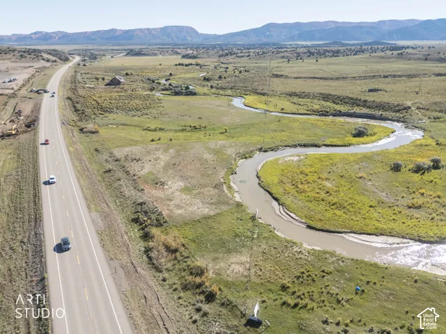 Expansive acreage featuring a winding creek, natural vegetation, and a prominent mountain range backdrop