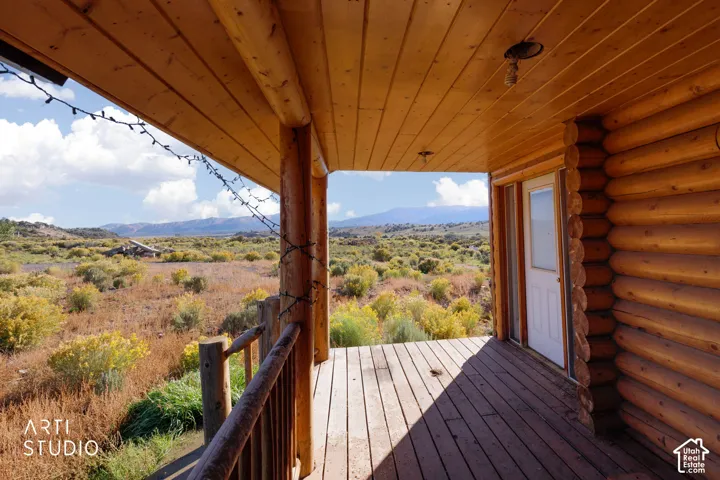 Covered log porch featuring timber-frame construction, tongue-and-groove wood ceiling, and mountain backdrop