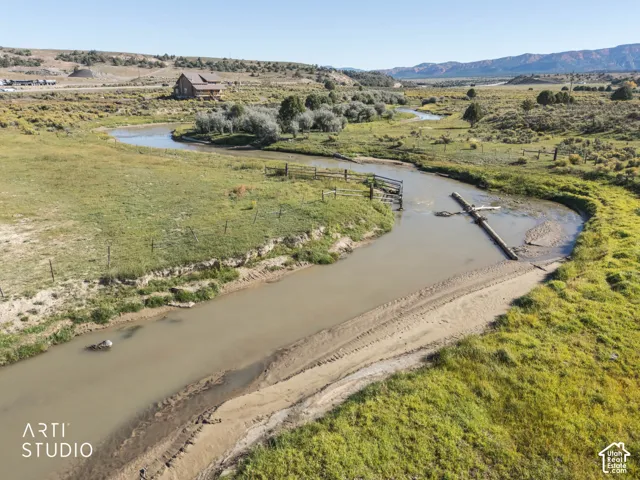Expansive acreage featuring a winding creek, natural grassy terrain, mature trees, and a mountain backdrop