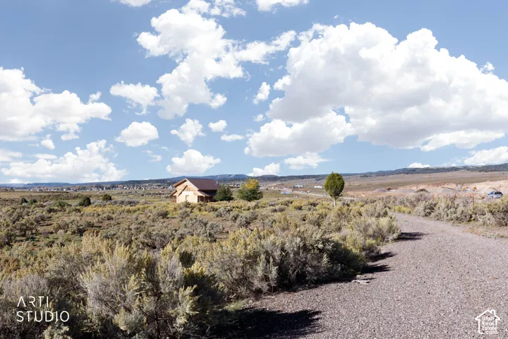 Expansive acreage featuring native high-desert vegetation, a gravel access road, and mountainous horizon